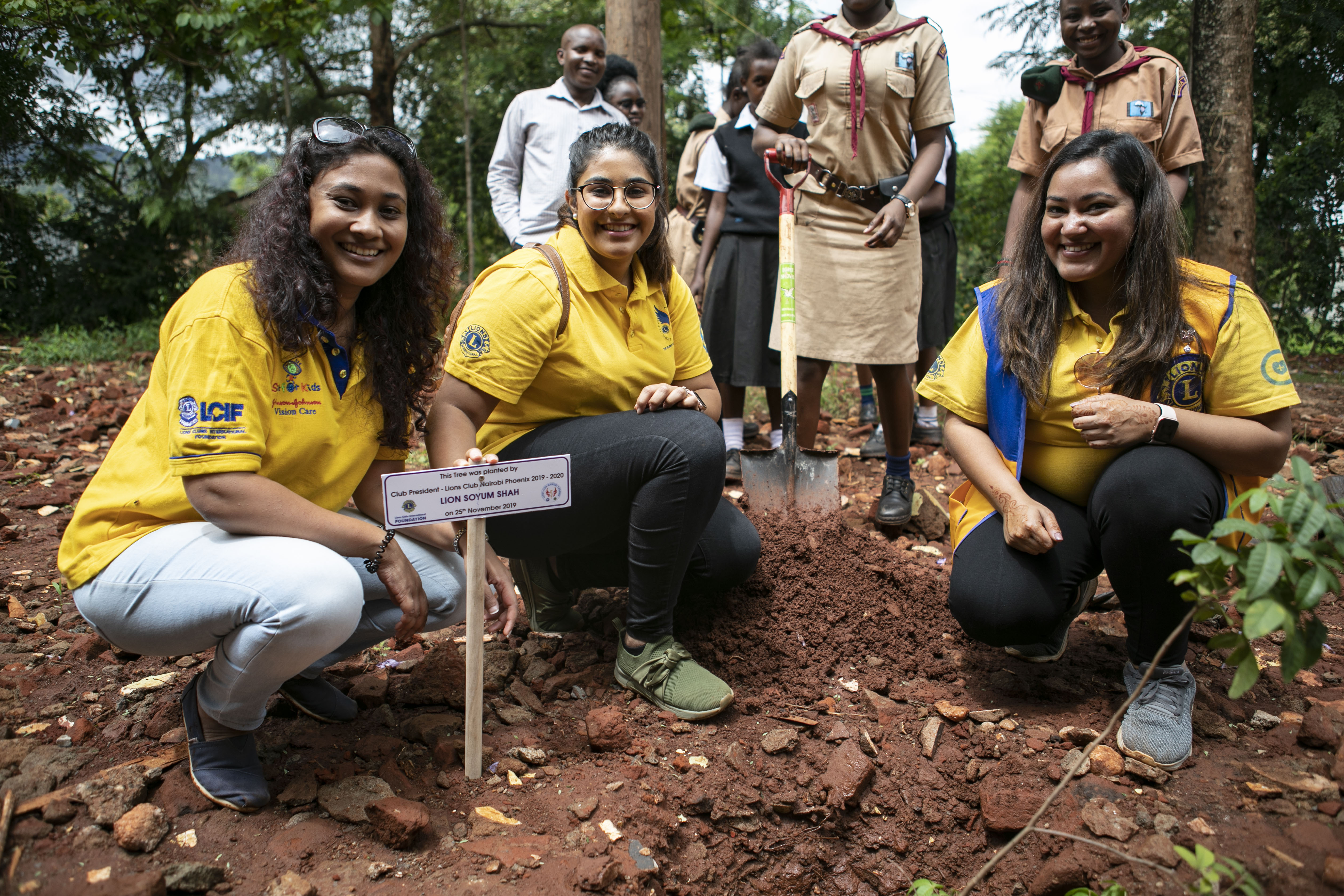 Three female Lions planting a tree.