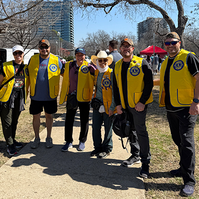 Mitglieder des Dallas Founder Lions Clubs stehen mit ihren gelben Westen im Freien, einsatzbereit für ein Community-Event.