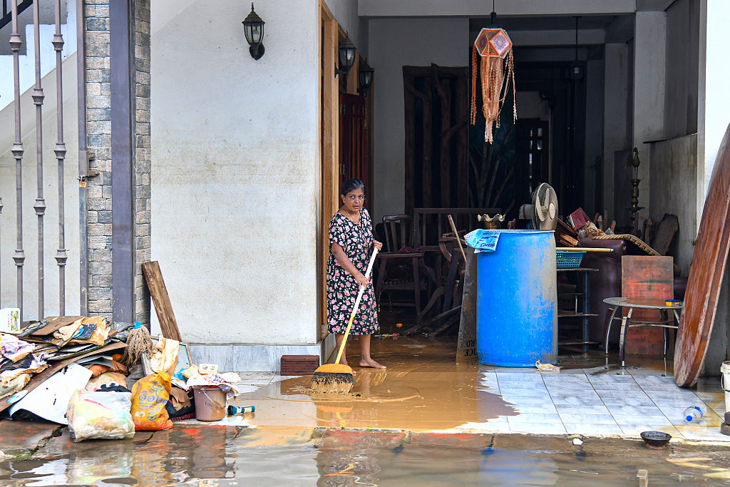 Woman cleaning mud and debris from her home after severe flooding