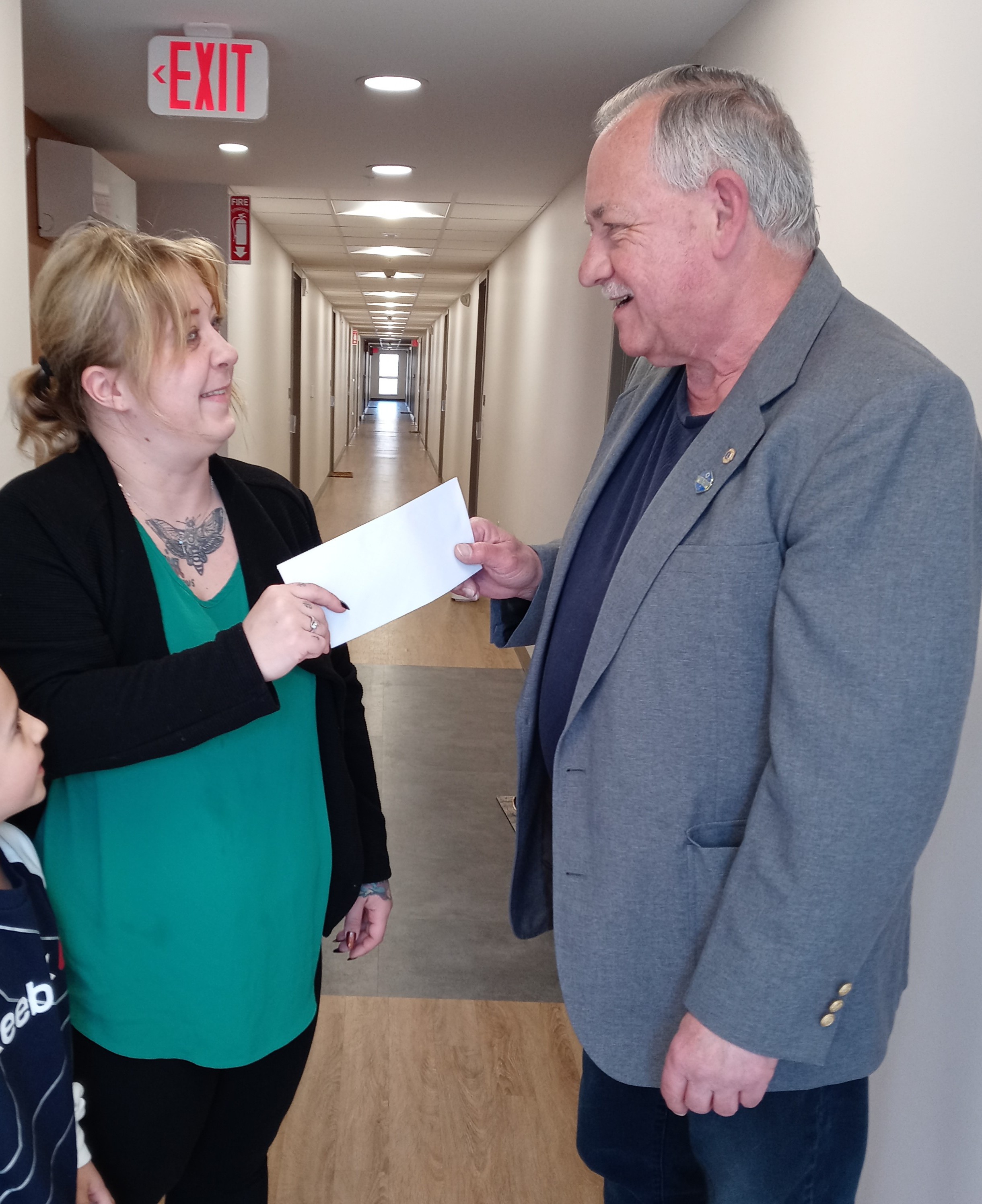 Il Lions John Juhasz consegna a Denise Faller, beneficiaria di un atto di gentilezza, una banconota da 100 dollari.